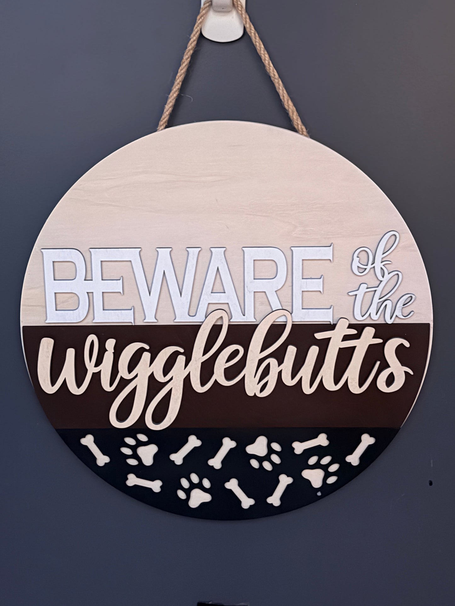 C2 Creative Crafts wooden round hanging sign with "Beware of the wigglebutts" text, paw prints, and bones.
