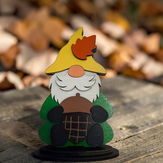 C2 Creative Crafts wooden gnome shelf sitter with yellow hat, white beard, green coat, holding a brown acorn. Autumn décor.