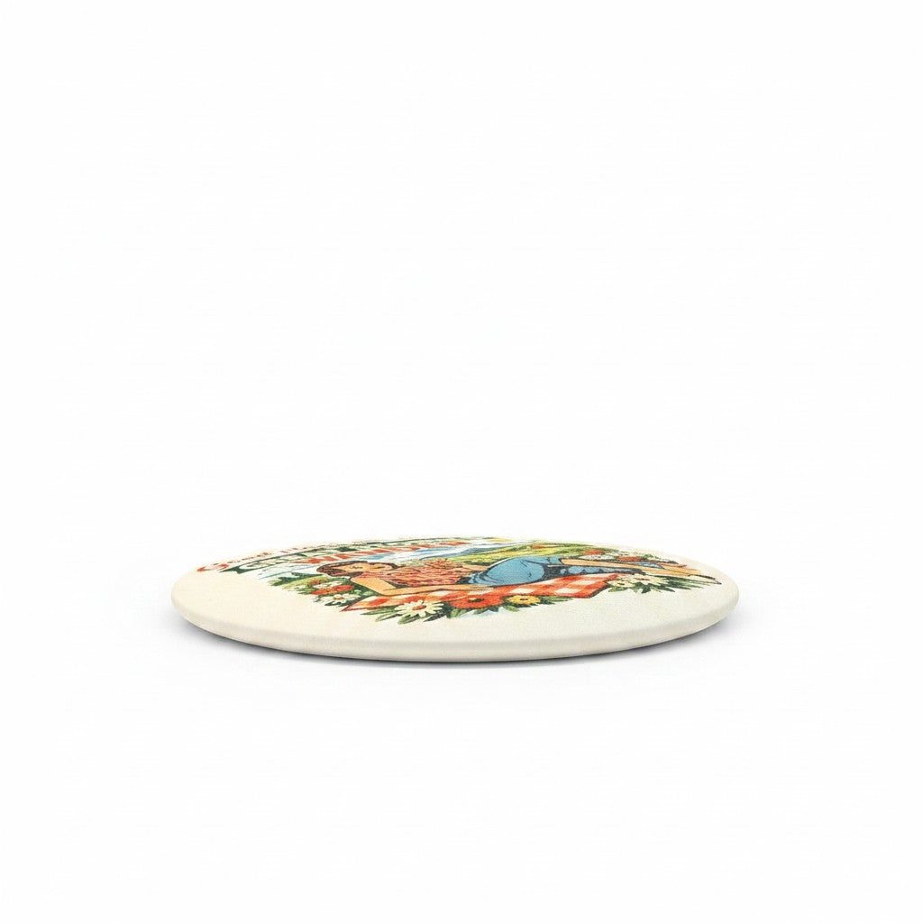 C2 Creative Crafts round art print featuring a retro picnic scene with a woman relaxing on a checkered blanket surrounded by flowers.